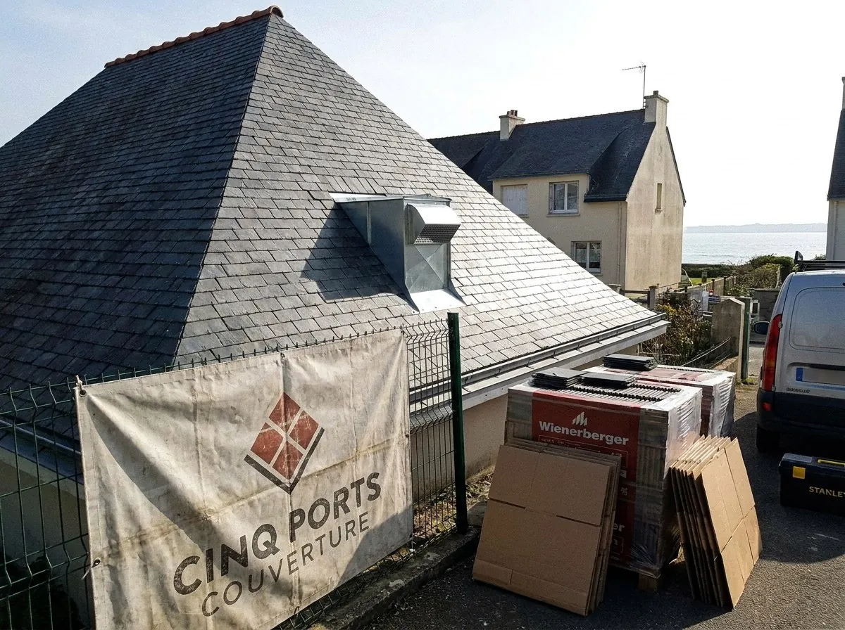 Toit en ardoise neuve refait par Cinq Ports Couverture près de Lorient, bâche de chantier au nom de l'entreprise et océan en bout de rue